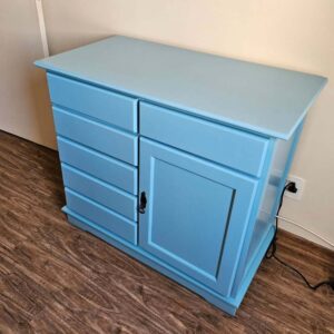 Cômoda restaurada com acabamento em laca azul vibrante e porta detalhada.