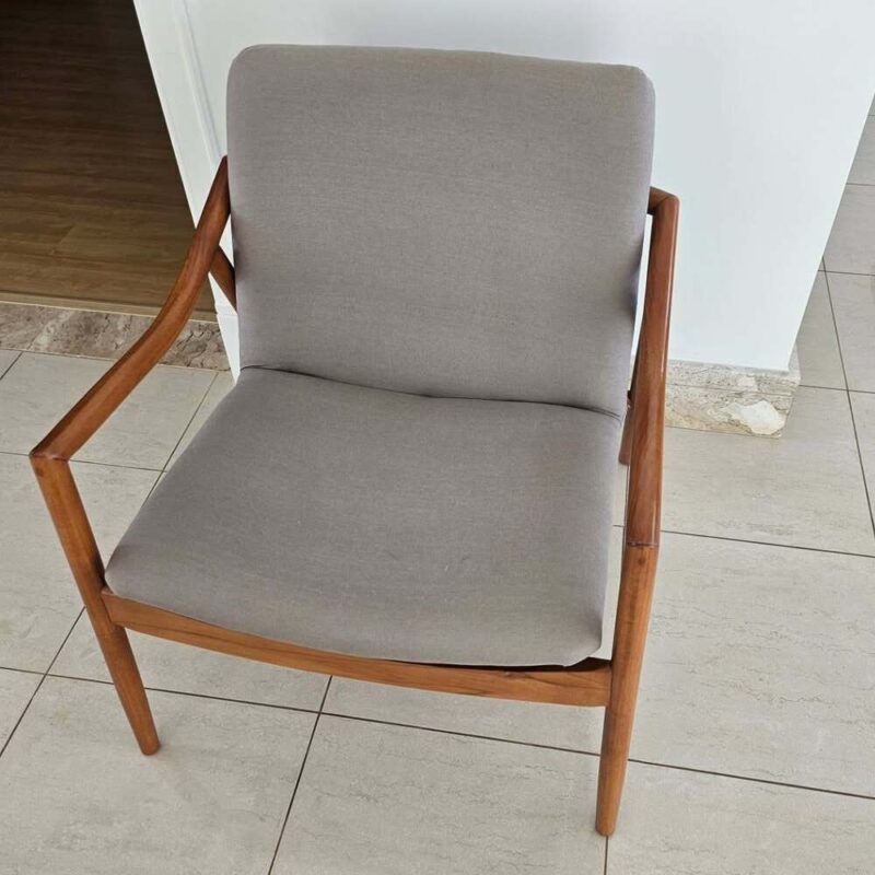 Poltrona restaurada com acabamento natural em verniz na estrutura de madeira e troca completa de tecido em cinza suave.